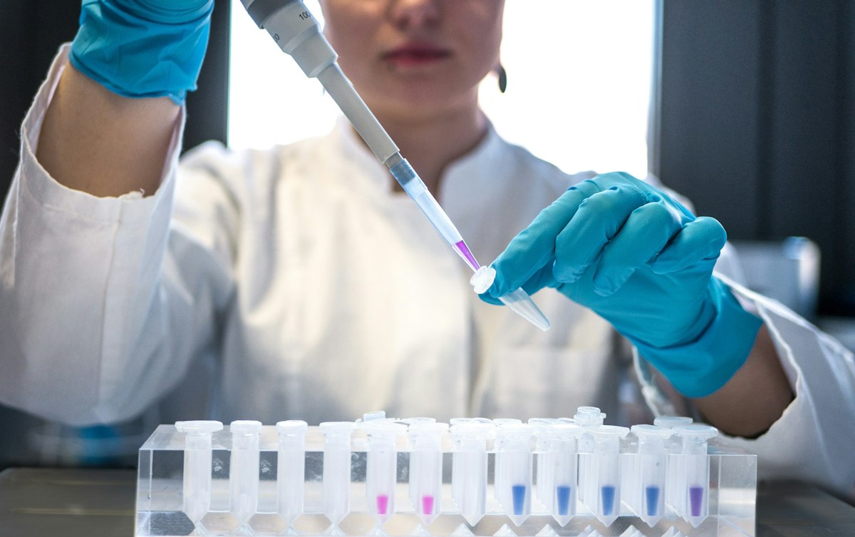 Technicienne de laboratoire pipetant un échantillon dans un tube d'analyse